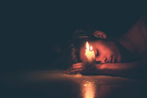 man asleep next to fading candle