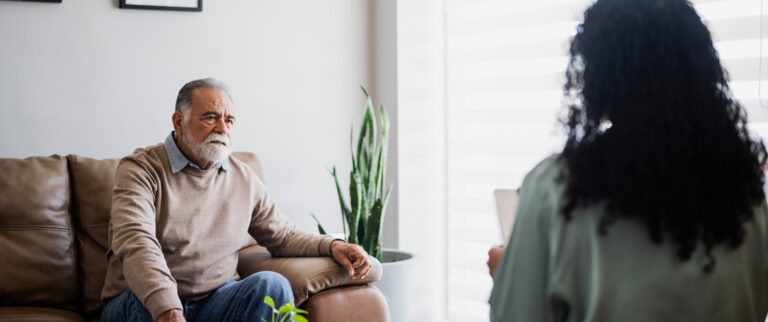 older man on sofa talks to woman opposite