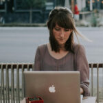 woman on laptop on patio of urban cafe