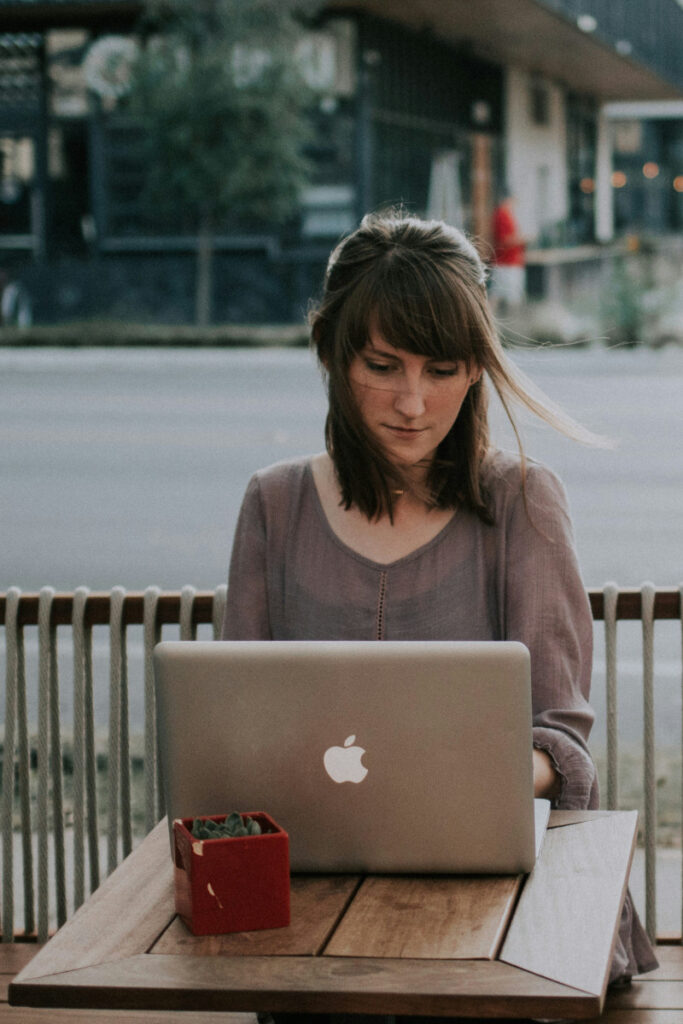 woman on laptop on patio of urban cafe