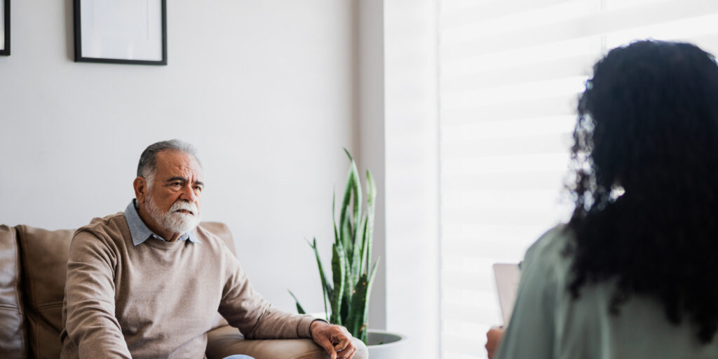 older man on sofa talks to woman opposite